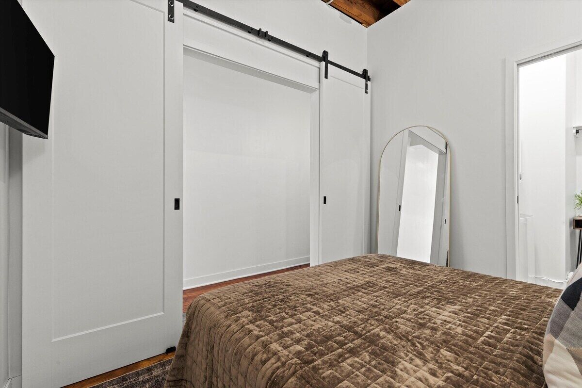 Ein Schlafzimmer mit einem Bett, einem Kleiderschrank und einem Spiegel.