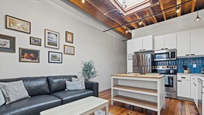 A modern kitchen with white cabinets, stainless steel appliances, and a blue backsplash. - Oak St. Loft #2 - Walk to T-Mobile, P&L, Streetcar (Kansas City)