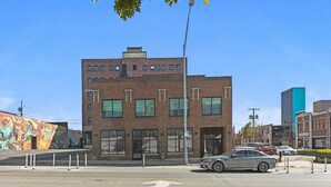 A multi-story building with a brick facade, large windows, and a parking lot with cars. - Oak St. Loft #2 - Walk to T-Mobile, P&L, Streetcar (Kansas City)