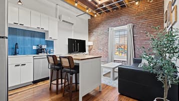 A modern kitchen with white cabinets, a blue backsplash, and a central island with bar stools.