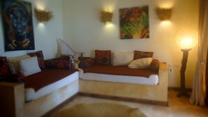 A cozy living room with a sofa set, decorative pillows, wall art, and a floor lamp. - AMANI BEACH VILLA (Bwejuu)