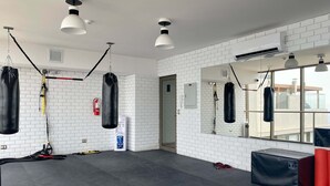 A gym with white brick walls, black punching bags, and a large mirror. - w* | Superb Loft w/ Balcony in Barranco (Lima)