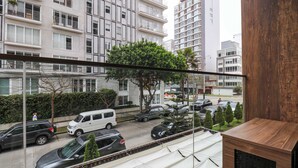 A view of a street with parked cars, a white van, and a tree in the foreground. - w* | Superb Loft w/ Balcony in Barranco (Lima)