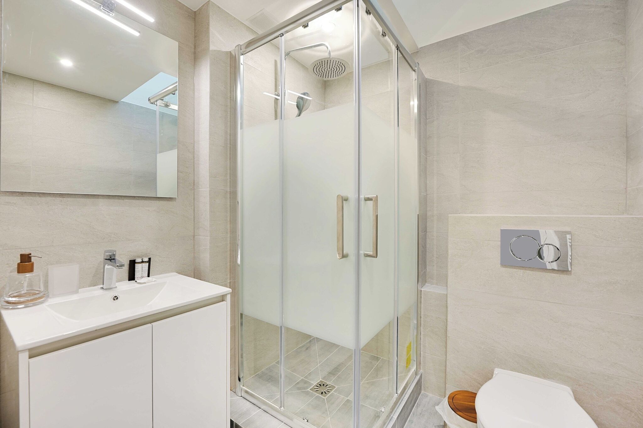 Ein modernes Badezimmer mit einer Duschkabine aus Glas, einem weißen Waschbecken und einer Toilette.