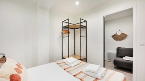 Una camera d'albergo con un letto, un tavolino, una sedia, un divano e una ventola decorativa.
