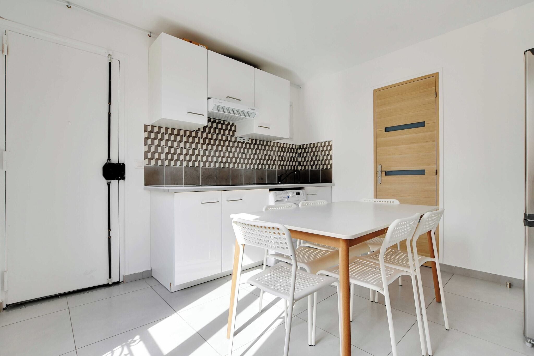 Una cocina moderna con armarios blancos, un salpicadero estampado y una puerta de madera.