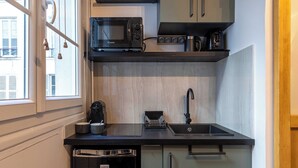 Una cocina compacta equipada con microondas, cafetera y lavabo.