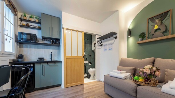 Un espacio habitable compacto con kitchenette, un sofá y una zona de comedor.