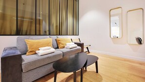 A modern living room with a grey sofa, a black coffee table, and a large window with curtains. - Haven of peace near the Palais de Garnier (Paris)
