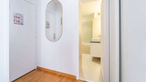 A hallway with a white door, a mirror, and a bathroom visible through an open door. - Charming studio- 2P- Jardin des plantes/Austerlitz (Paris)