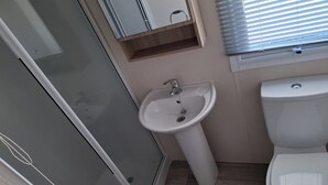 A bathroom with a glass shower enclosure, a pedestal sink, and a toilet. - 2 bed Caravan in Rhyl , dog Friendly, With Wifi (Rhyl)