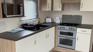 A compact kitchen with a microwave, toaster, kettle, stove, and oven. - 2 bed Caravan in Rhyl , dog Friendly, With Wifi (Rhyl)