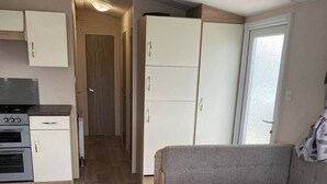 A compact living space with a kitchenette, a sofa, and a dining table. - 2 bed Caravan in Rhyl , dog Friendly, With Wifi (Rhyl)
