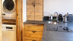 Eine kleine Küche mit Waschmaschine, Holzschränken, Spüle und verschiedenen Küchenutensilien.