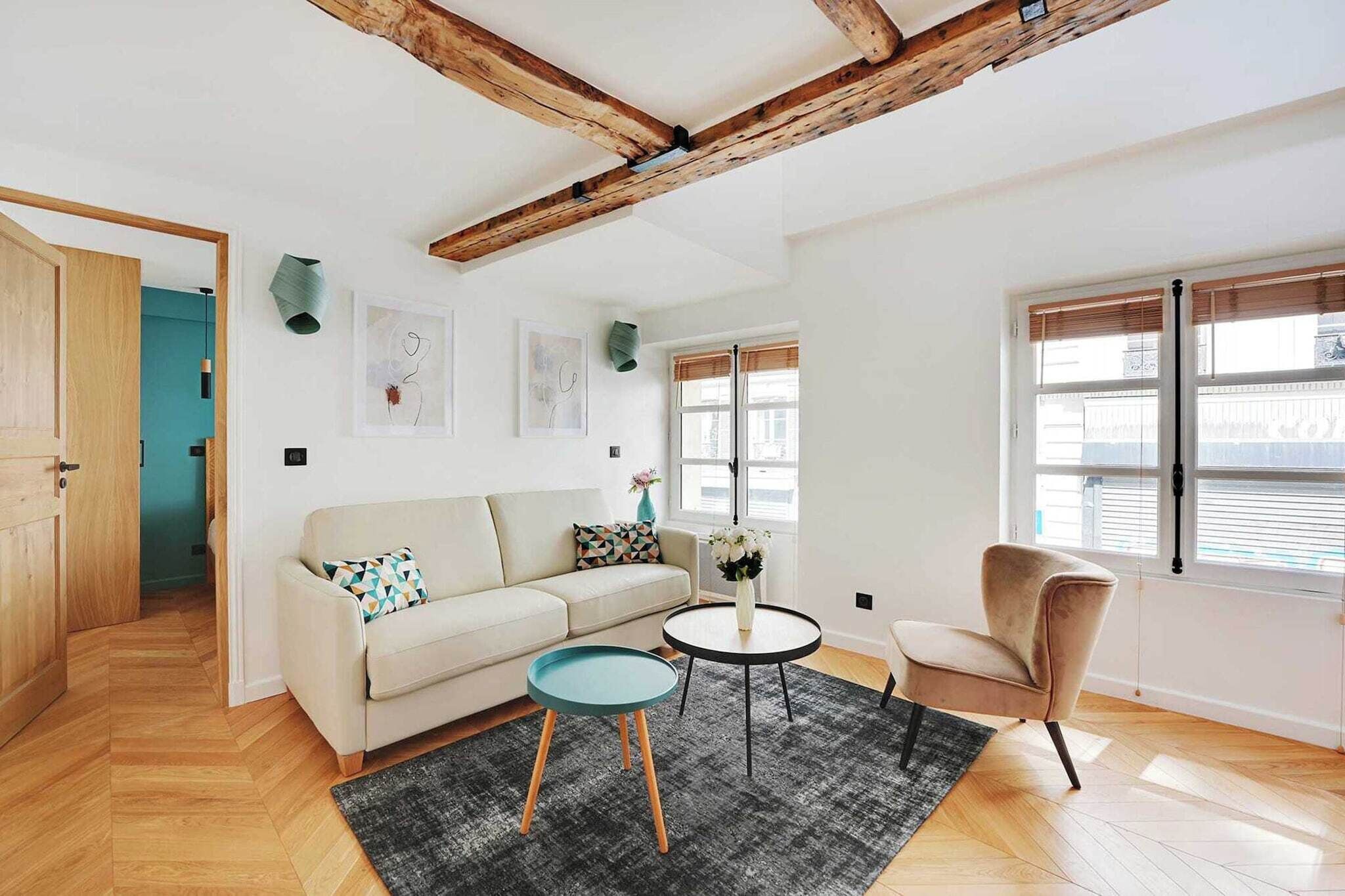 A modern living room with a wooden ceiling, a sofa, a round coffee table, a chair, and a window with blinds.