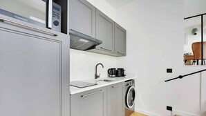 A compact kitchen with a built-in microwave, a coffee maker, and a washing machine.