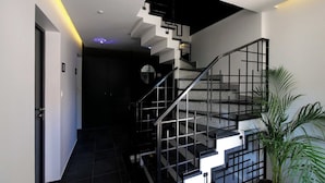 Eine moderne Treppe mit schwarzen Geländern und einem Rundfenster am oberen Ende.