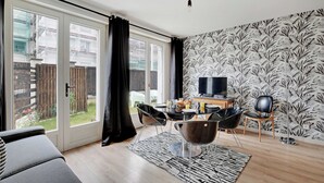 Ein modernes Wohnzimmer mit Essbereich, großen Schiebeglastüren zum Garten und einem Flachbildfernseher, versehen mit einem gemusterten Wandpapier.