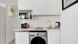 A compact kitchen with a microwave, coffee maker, sink, and dishwasher.