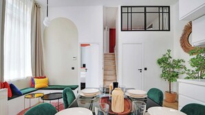 Ein moderner, kompakter Wohnraum mit Essbereich, einer Treppe und Blick auf eine rote Wand.