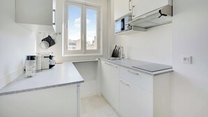 Une cuisine moderne avec des meubles blancs, un four à micro-ondes encastré et une fenêtre qui laisse entrer la lumière naturelle.