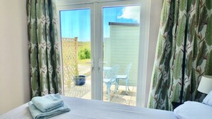 Un dormitorio con cama, ventana y vistas a un patio exterior con una silla y una planta en maceta.