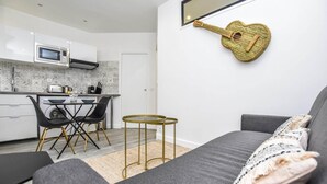 A modern kitchen with white cabinets, a microwave, and a small dining area with a table and chairs. - Cosy apartment - 1BR/4P - Auteuil (Paris)