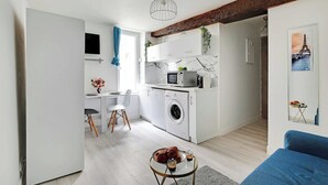 A compact living space with a kitchenette, a dining area, and a seating area. - Cozy Studio in the heart of the Marais (Paris)