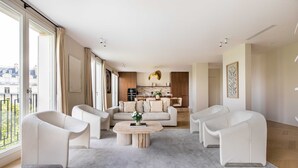 Ein modernes Wohnzimmer mit einer Sofagarnitur, einem Couchtisch und einer Küche im Hintergrund.
