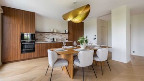 Eine moderne Küche mit eingebautem Backofen und Essbereich mit Holztisch und Stühlen.