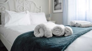 Una cama bien hecha con sábanas blancas y un edredón color turquesa.