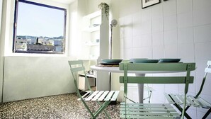 Una cocina compacta con ventana, una mesa de comedor con sillas y un salpicadero de azulejos blancos.