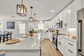 Una cocina moderna con armarios blancos, una isla central e iluminación colgante.