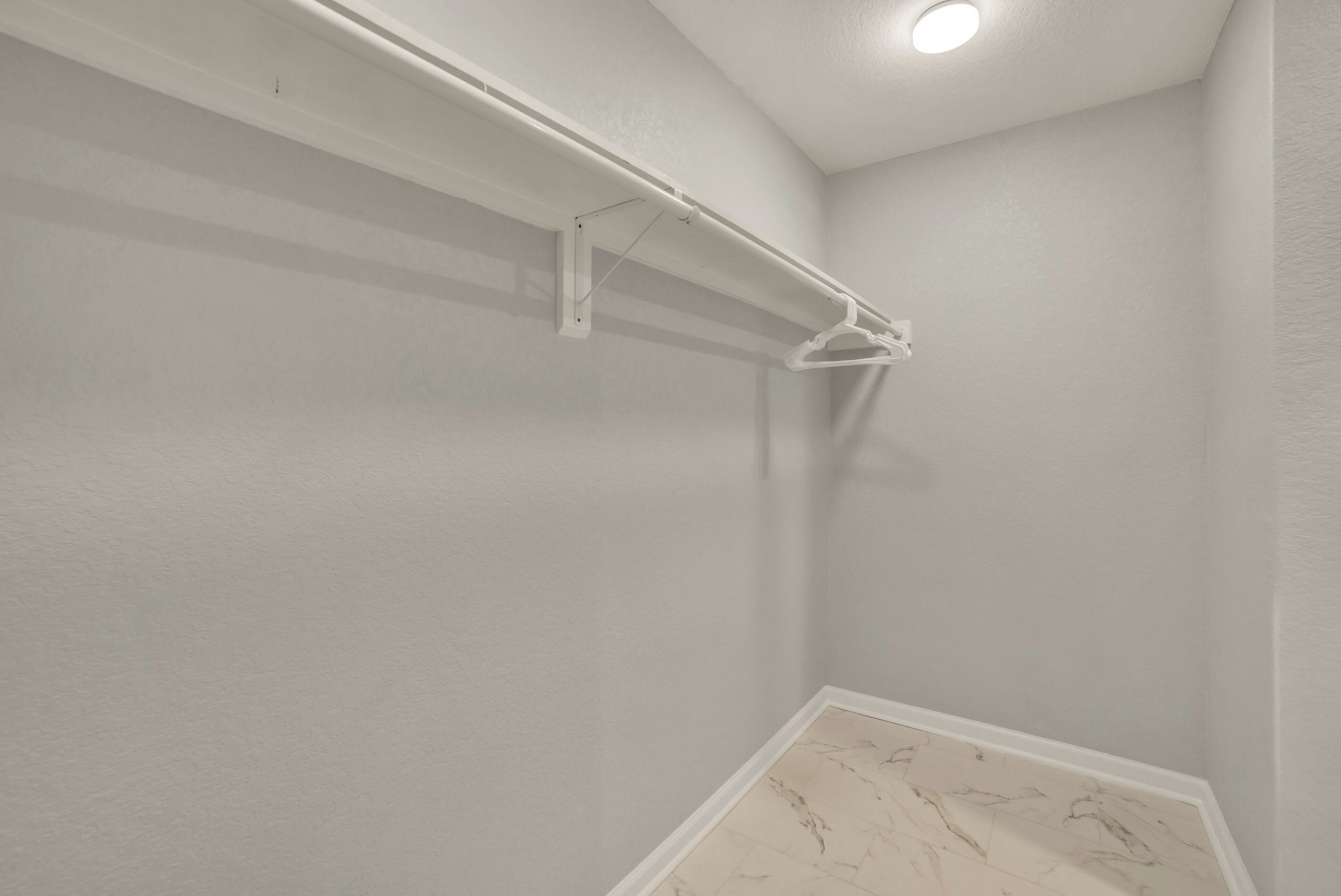 Eine Raumecke mit weißer Wand, Marmorboden und weißer Decke mit eingelassener Beleuchtung.