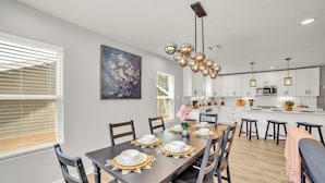 Una cocina moderna con armarios blancos, una isla central e iluminación colgante.