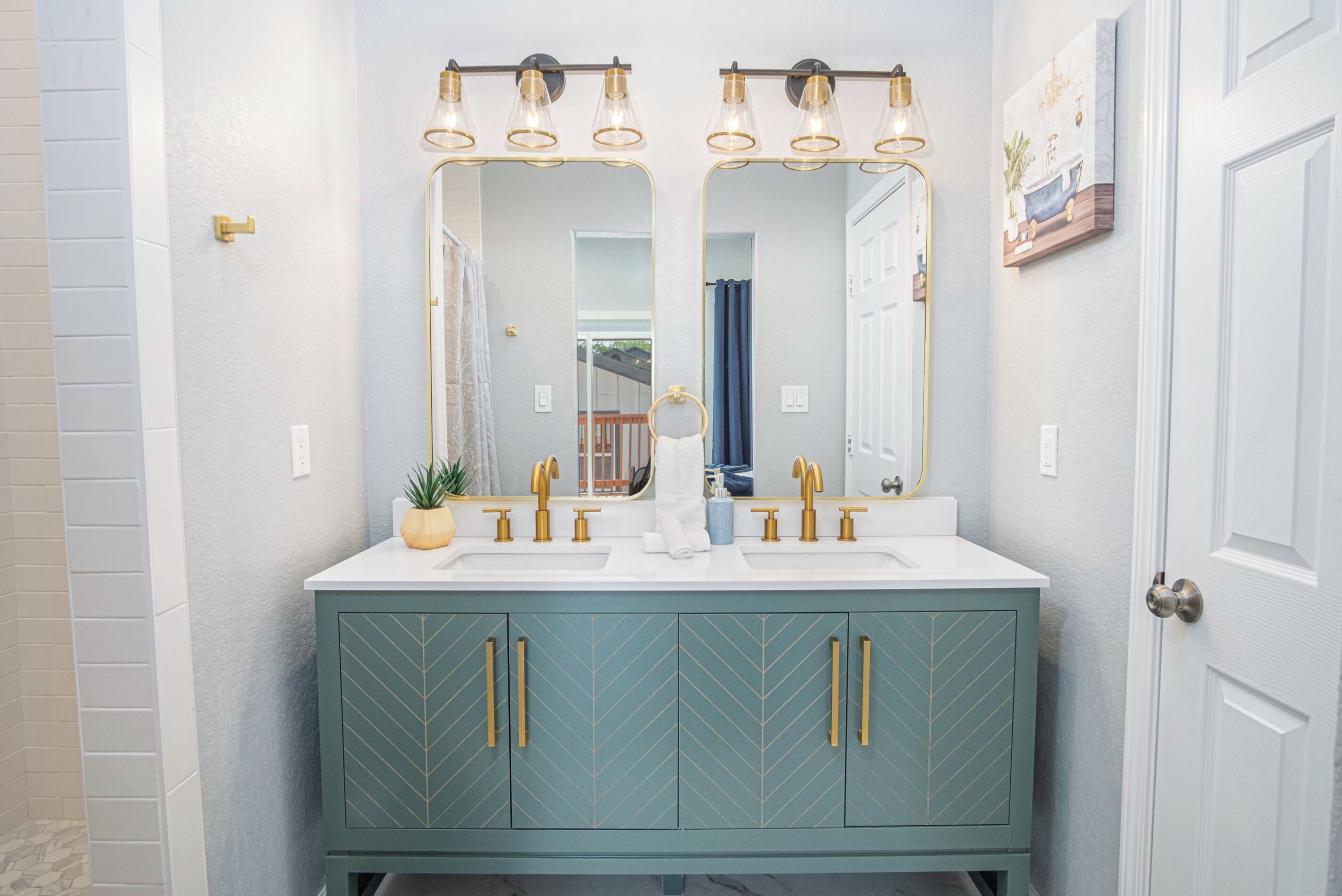Une salle de bain avec un meuble-lavabo blanc, deux robinets dorés et un miroir doté de trois points lumineux.