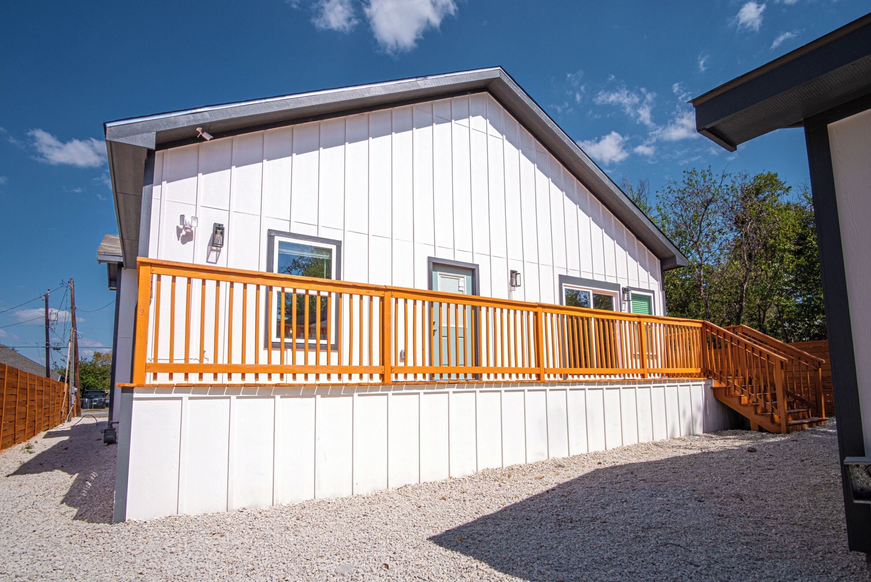 A white building with a wooden deck and a staircase.