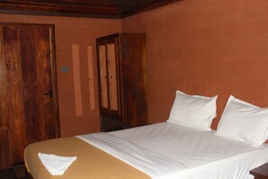 Habitación de hotel con cama, armario de madera y pared de ladrillo.