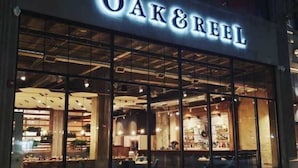A storefront with large glass windows and the name "OAK&REEL" illuminated above. - 2BR Exclusive Retreat Near Henry Ford (Detroit)