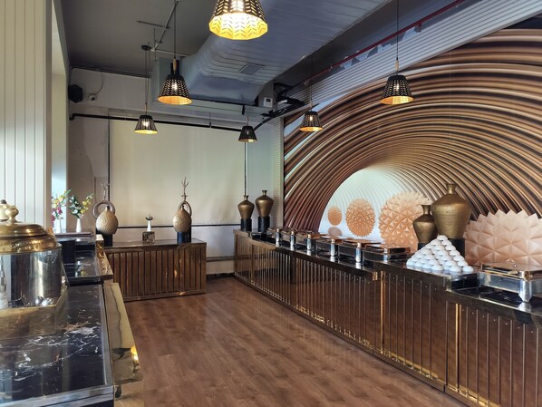 Un área de bar moderna con mostradores de madera y encimeras de mármol negro, además de jarrones decorativos.