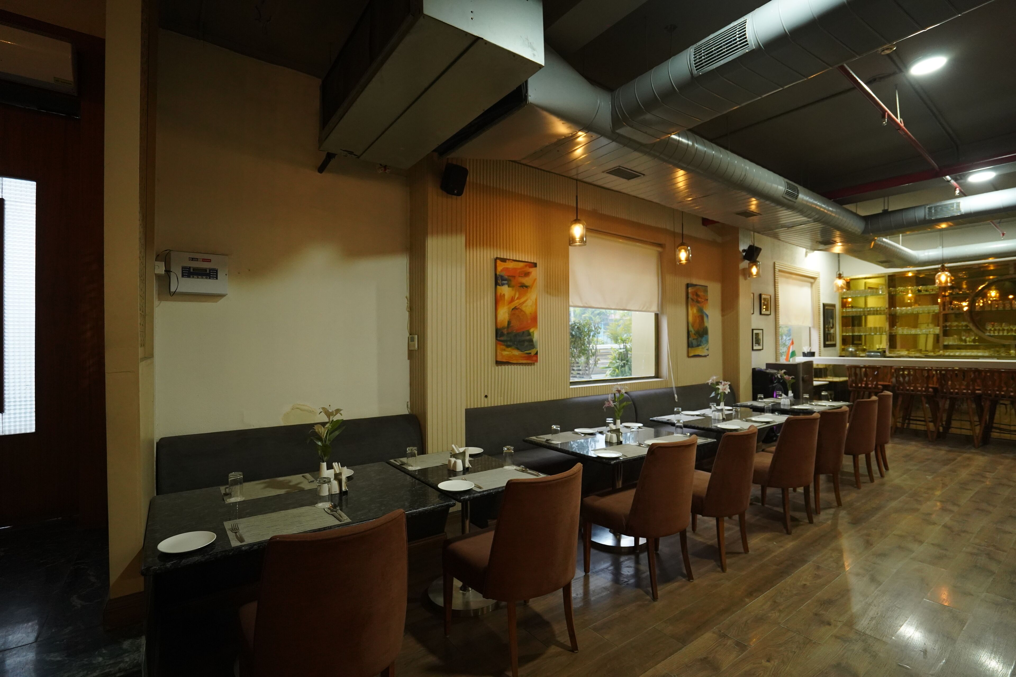 A restaurant with multiple dining tables and chairs, a bar area, and a large window with a view.