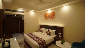 A hotel room with a bed, bedside table, and a small round table with a plant. - Hotel Luxe Opera NH8 - 7km from IGI Delhi Airport (New Delhi)