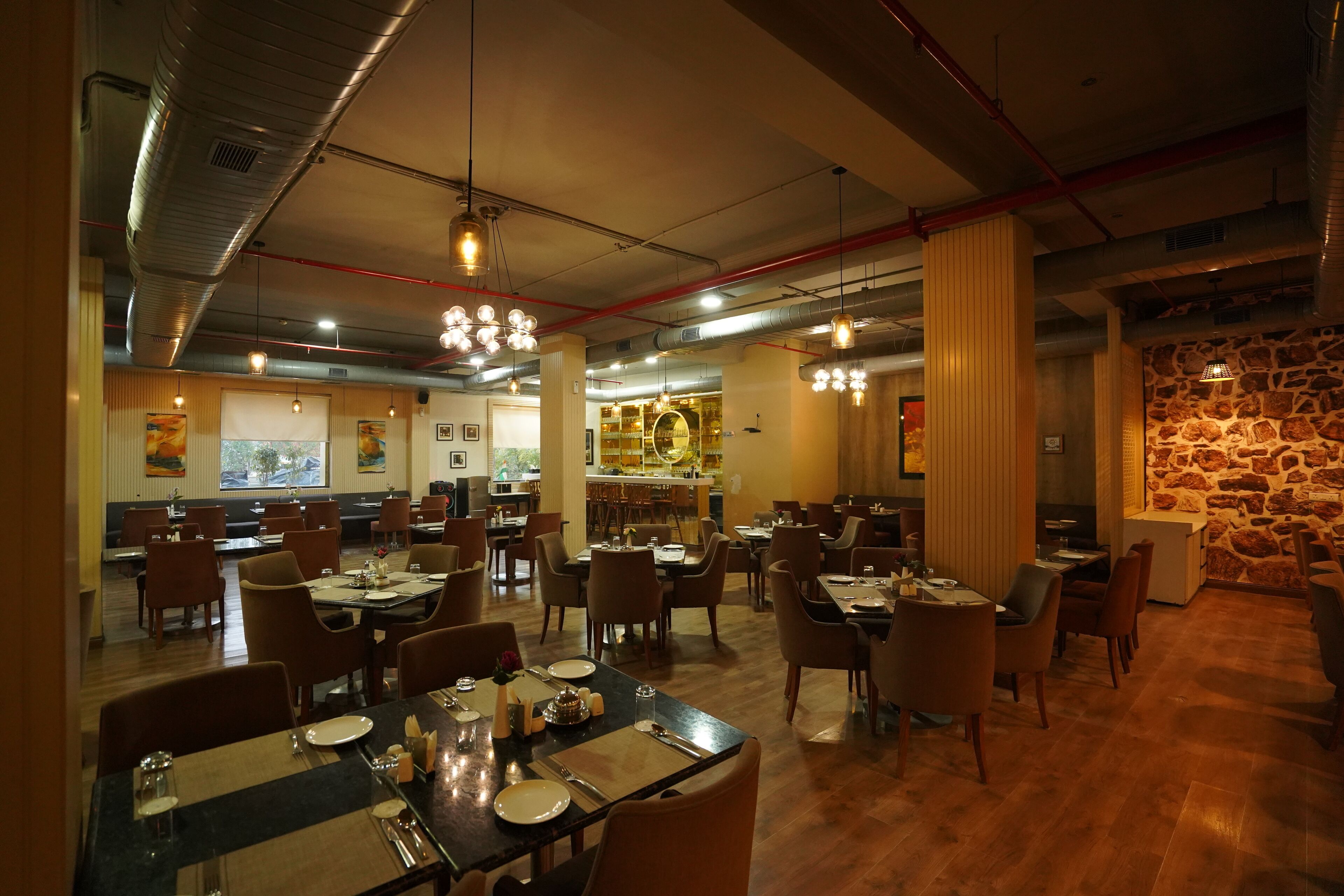 Un restaurant doté de plusieurs tables et chaises, d’un bar et d’un mur en pierre.