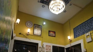 Una habitación con paredes amarillas, un candelabro, azulejos decorativos y dos puertas negras.