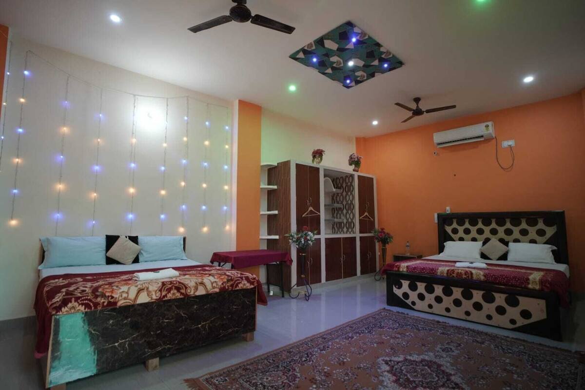 Une chambre avec deux lits, une armoire, des ventilateurs de plafond et des luminaires décoratifs.