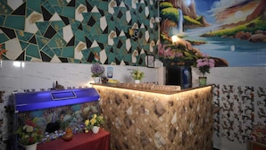 Zona de recepción con mostrador de entrada, un acuario y un mural de un paisaje.