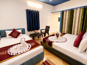 Habitación de hotel con dos camas, una mesita, una silla y vistas al exterior.