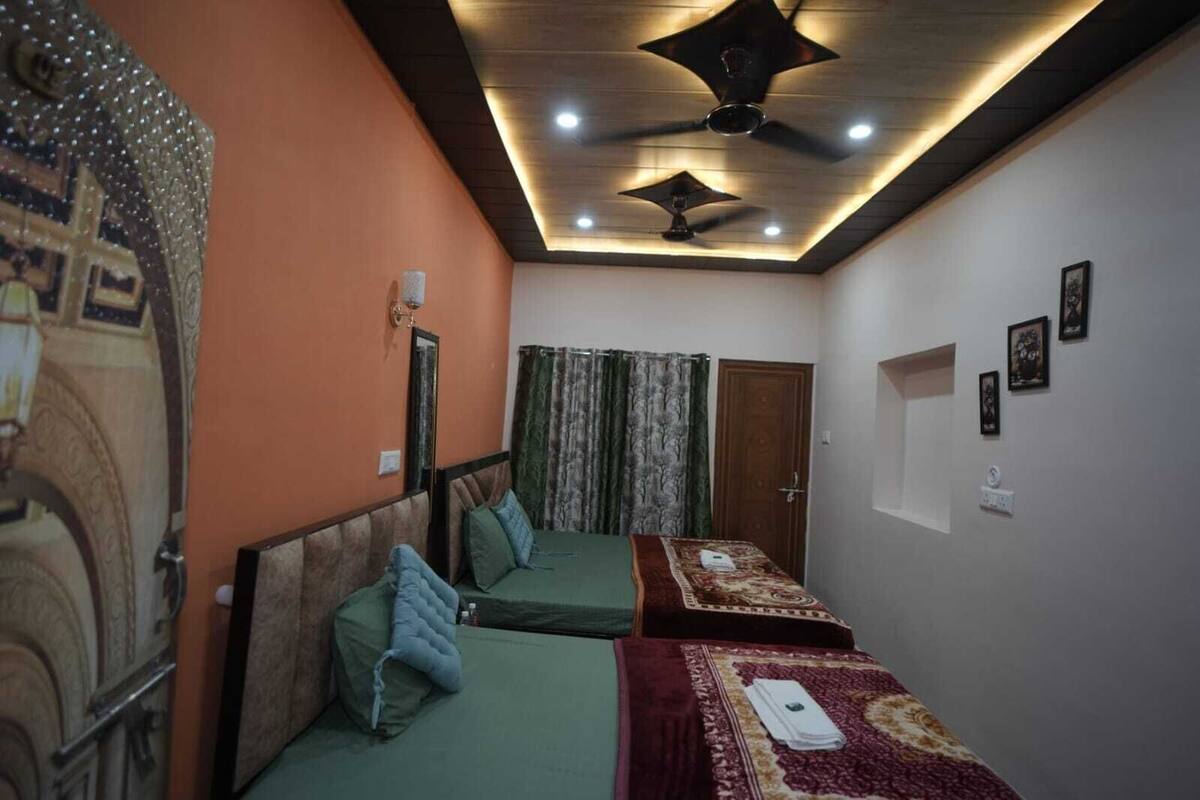 Une chambre avec deux lits, un ventilateur de plafond et une porte.
