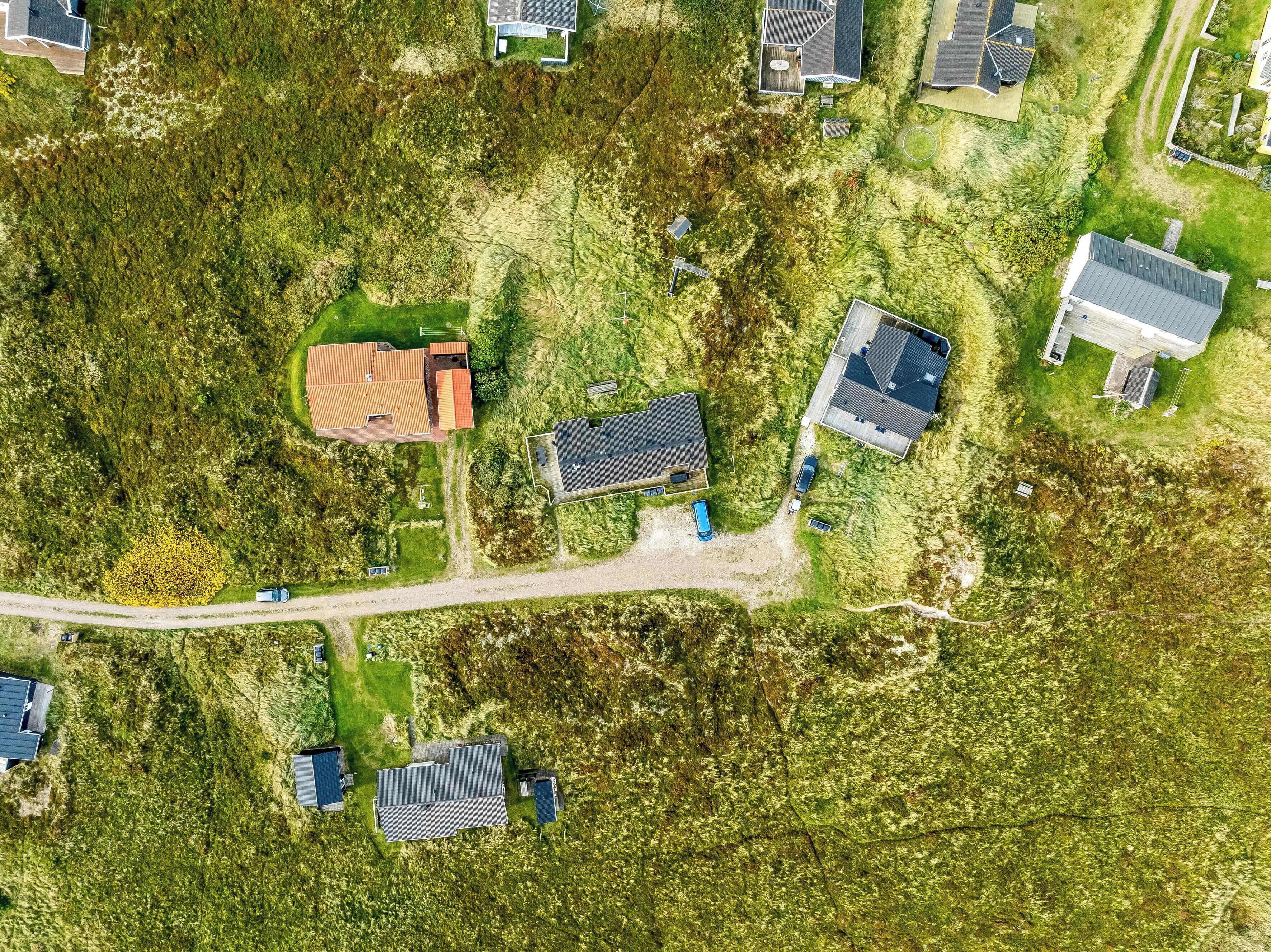 Ett flygbildsbild av ett bostadsområde med flera hus, vägar och grönområden.