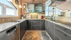 Een moderne keuken met granieten aanrechtbladen, roestvrijstalen apparatuur en houten accenten.